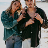 A male and female model on a beach, the man wearing the Billie Jo Rope Necklace which complements his casual, coastal style.