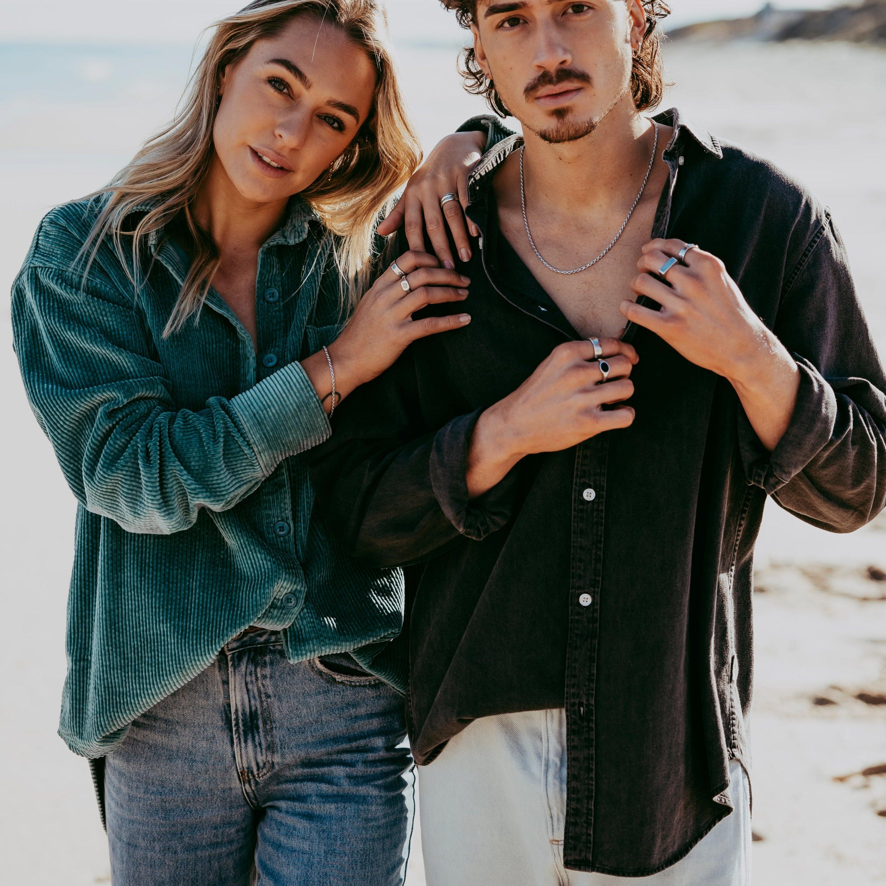 A male and female model on a beach, the man wearing the Billie Jo Rope Necklace which complements his casual, coastal style.