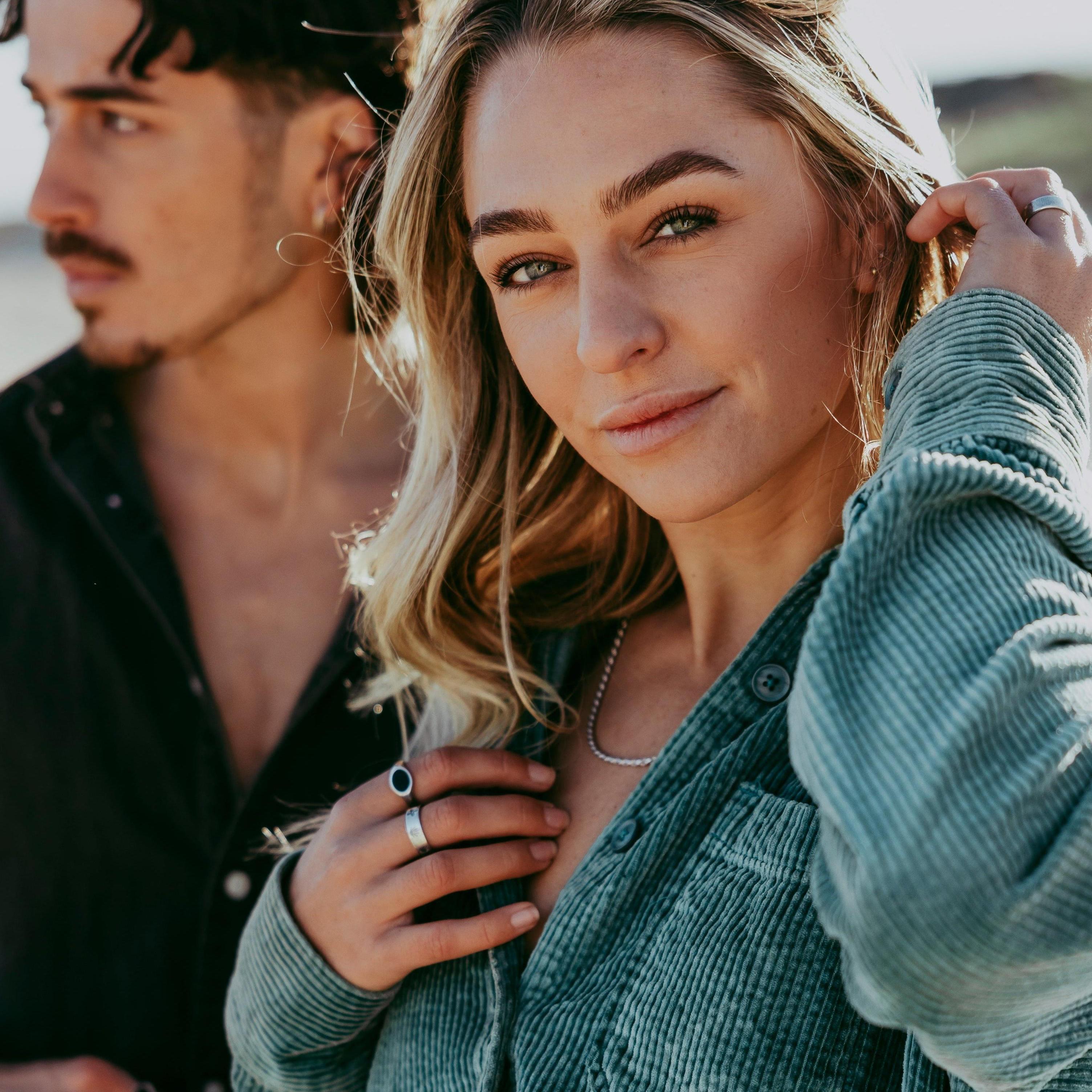 A woman with blonde hair wears the Billie Jo Rope Necklace, layered over a green corduroy shirt, showcasing the brand's versatile and stylish men's jewellery.