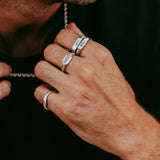 A man wearing the sterling silver Rosa Stacker rings from Billie Jo, styled with a silver chain against a black t-shirt for a modern, masculine look.