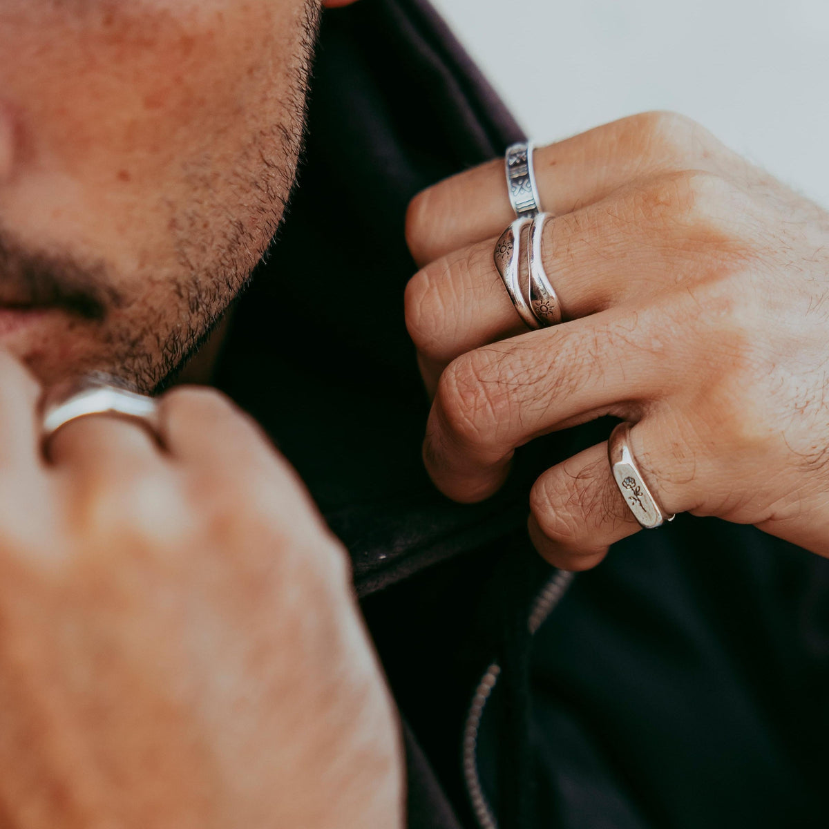 A close-up on a man's hands as he adjusts his collar, wearing the Rosa II ring and other silver jewellery from Australian brand Billie Jo. A modern, masculine look.