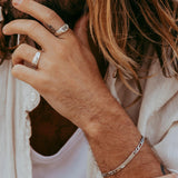 A close-up lifestyle shot of the men's sterling silver Persona Bracelet by Billie Jo, shown on a model's wrist with his hand running through his hair.