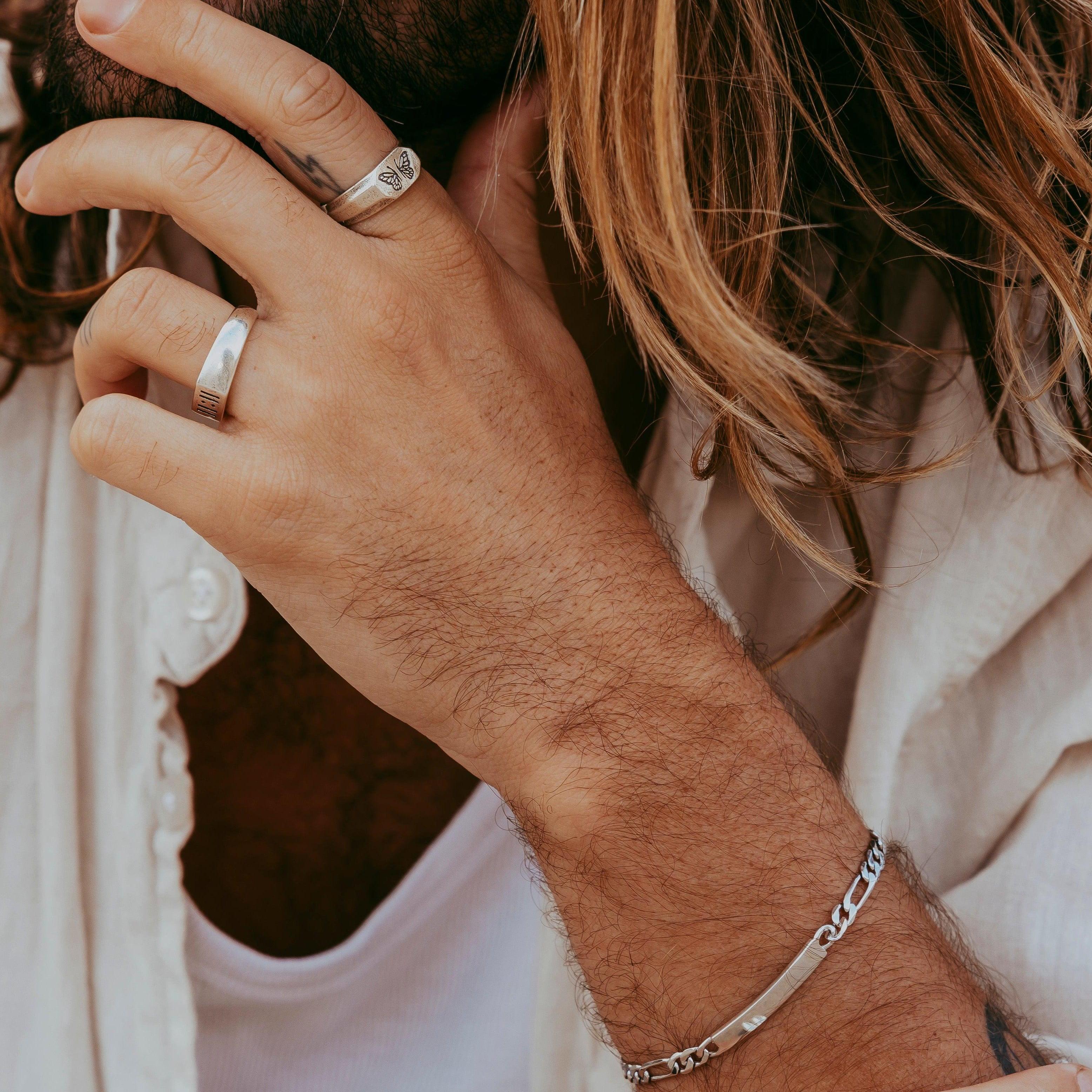 A close-up lifestyle shot of the men's sterling silver Persona Bracelet by Billie Jo, shown on a model's wrist with his hand running through his hair.