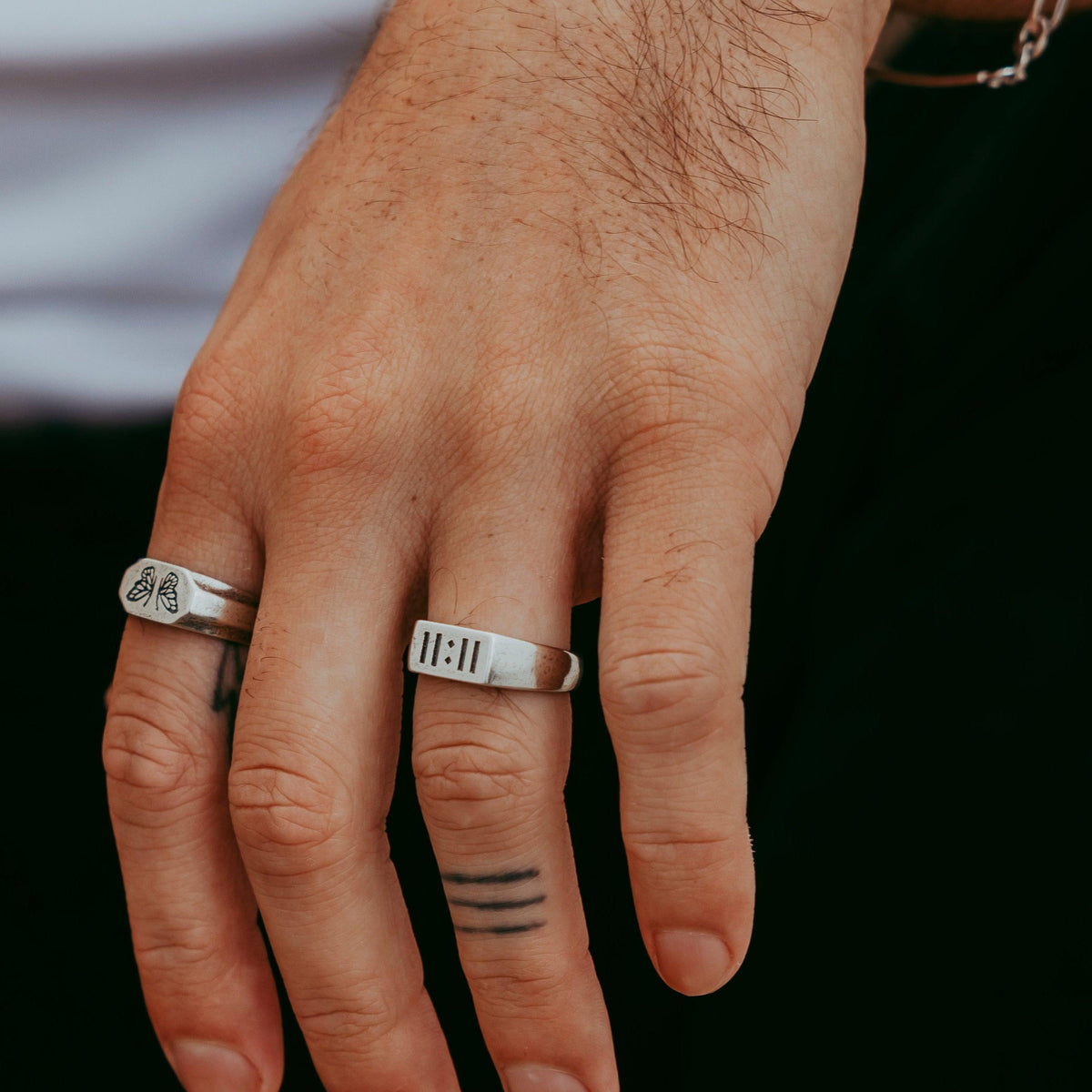 A man's hand wearing the sterling silver Momento Ring from Australian jewellery brand Billie Jo, styled with another signet ring for a modern, layered look.