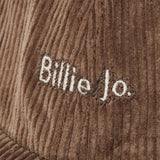 A macro shot of the 'Billie Jo' logo embroidered in white on the rich brown corduroy of the Corduroy Hat, showcasing the texture and quality.