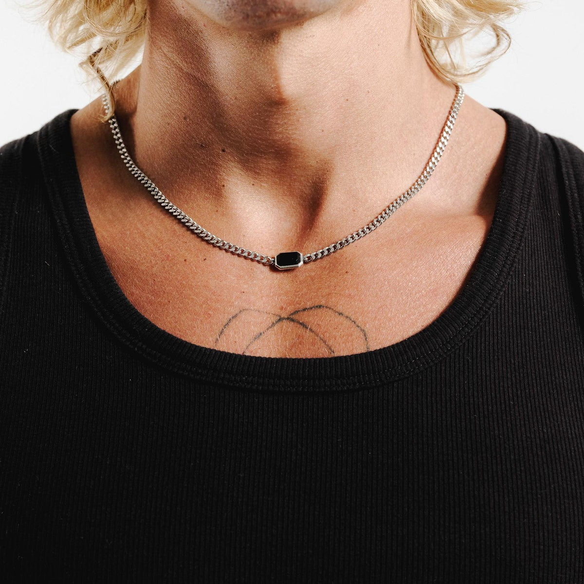 A man wearing the sterling silver Eclipse Necklace from Billie Jo, styled with a black tank top to showcase the black onyx stone.