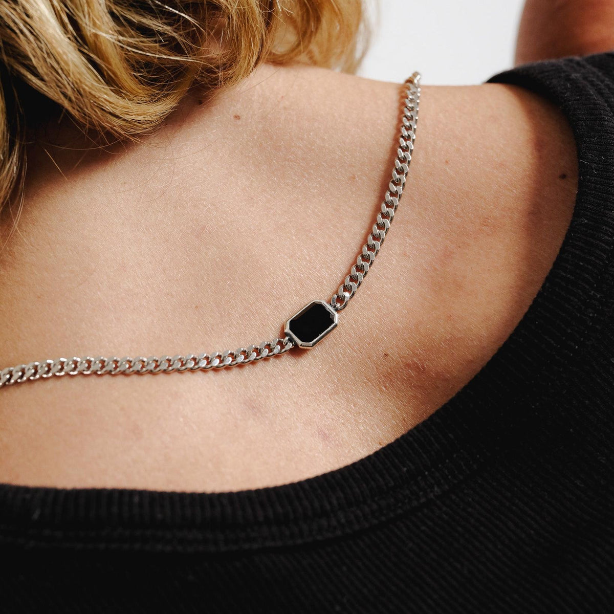 A close-up of the Billie Jo Eclipse Necklace from behind, showing the sterling silver curb chain and black onyx stone on a man's neck.