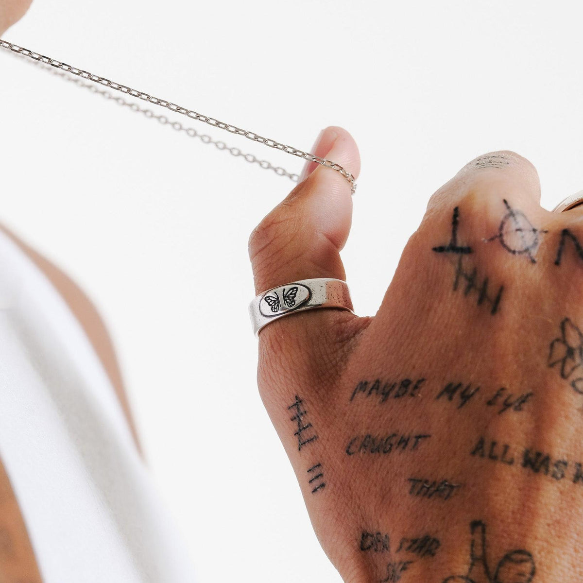 The Elaris Ring by Billie Jo, styled on a tattooed hand. This sterling silver butterfly ring adds a unique touch to any modern men's jewellery collection.