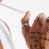 Close-up of the Slim Batch Necklace chain by Billie Jo, held by a man with hand tattoos, showcasing the fine craftsmanship of the silver links.
