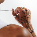 A unique view of the Elaris Ring by Billie Jo, worn on a tattooed hand. This sterling silver men's ring adds a touch of individuality to any outfit.