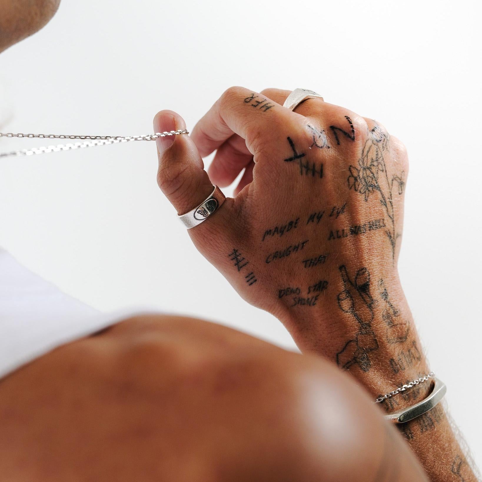 A unique view of the Elaris Ring by Billie Jo, worn on a tattooed hand. This sterling silver men's ring adds a touch of individuality to any outfit.