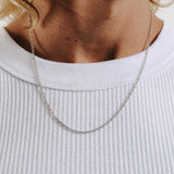 A man wearing the sterling silver Slim Batch Necklace from Billie Jo, styled with a simple white ribbed tank top for a modern, everyday look.