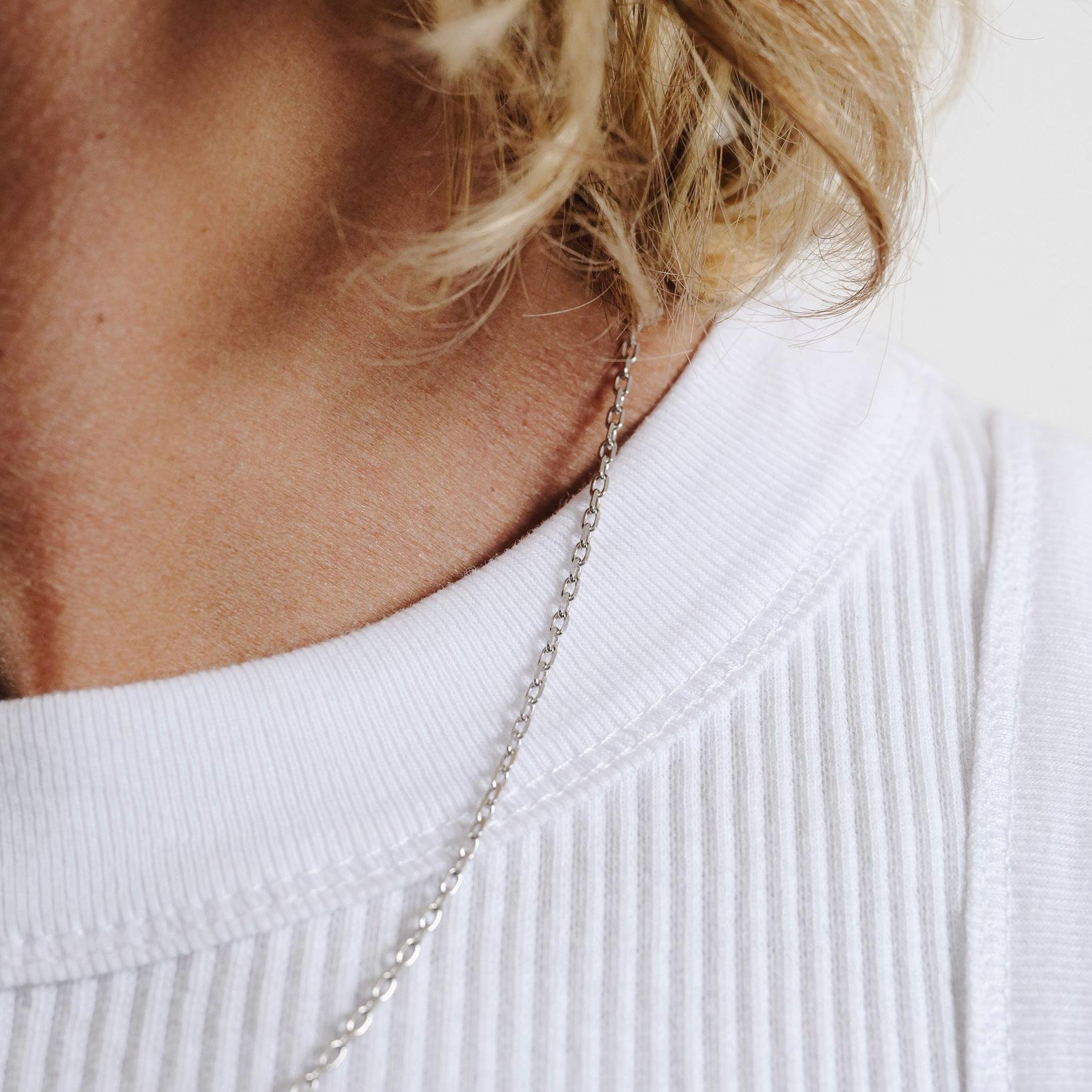 Side view of a man with blonde hair wearing the Slim Batch Necklace, showing how the sterling silver chain sits elegantly on the collarbone.