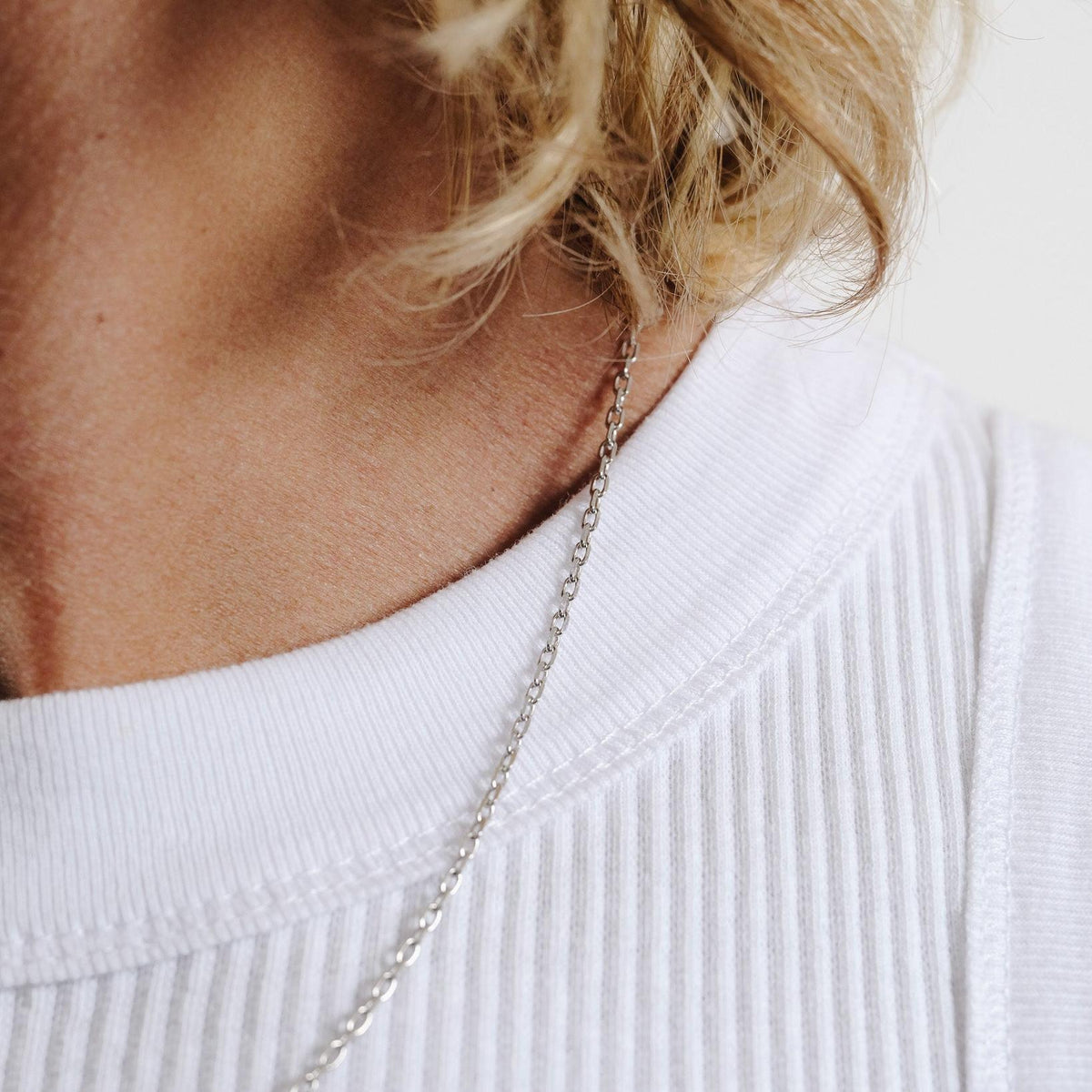 Side view of a man with blonde hair wearing the Slim Batch Necklace, showing how the sterling silver chain sits elegantly on the collarbone.