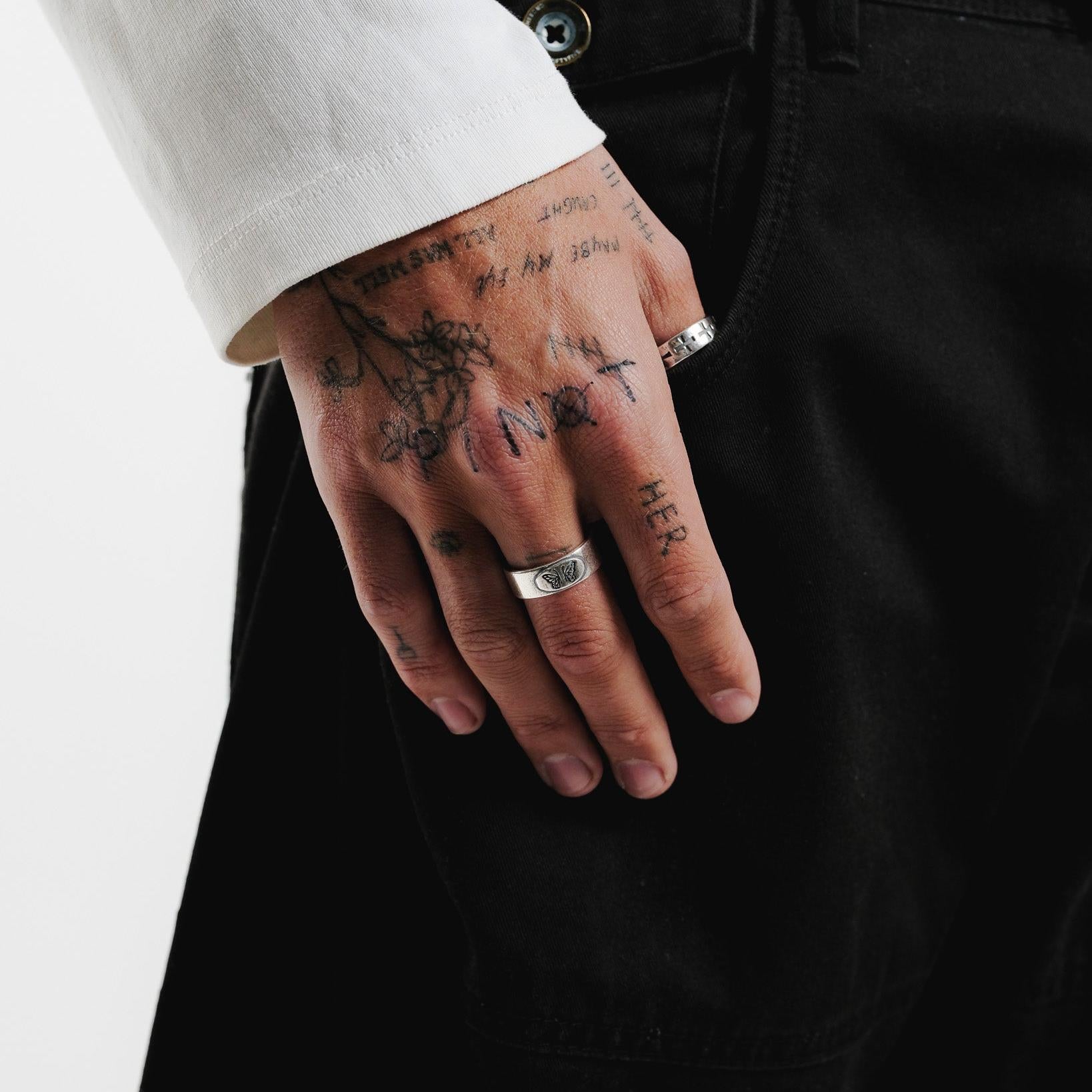 The Elaris Ring by Billie Jo, a sterling silver butterfly ring, seen on a tattooed hand. A subtle yet stylish piece of Australian men's jewellery.