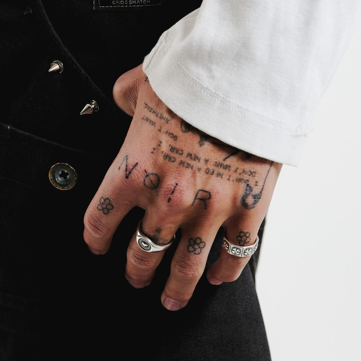 A close-up on-hand shot of the Vita Ring, worn on the ring finger, with the hand resting on a pair of black pants. This image highlights the ring's unique design in a styled context for Billie Jo.