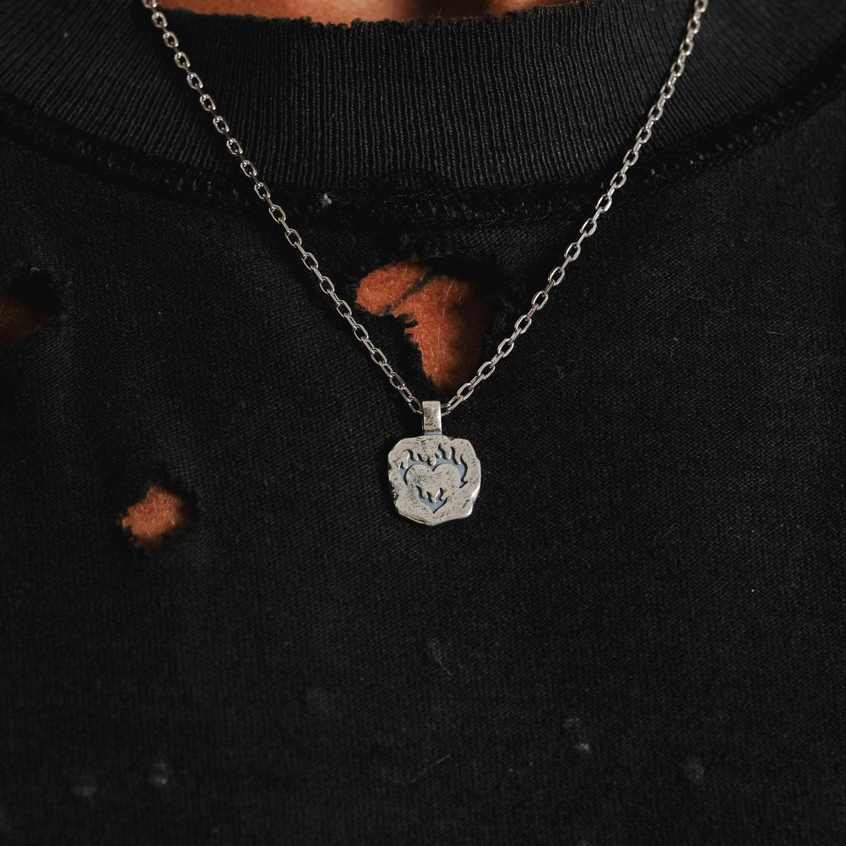 A close-up of the Billie Jo Ember Pendant worn against a black, distressed t-shirt, highlighting the sterling silver's contrast and modern aesthetic.
