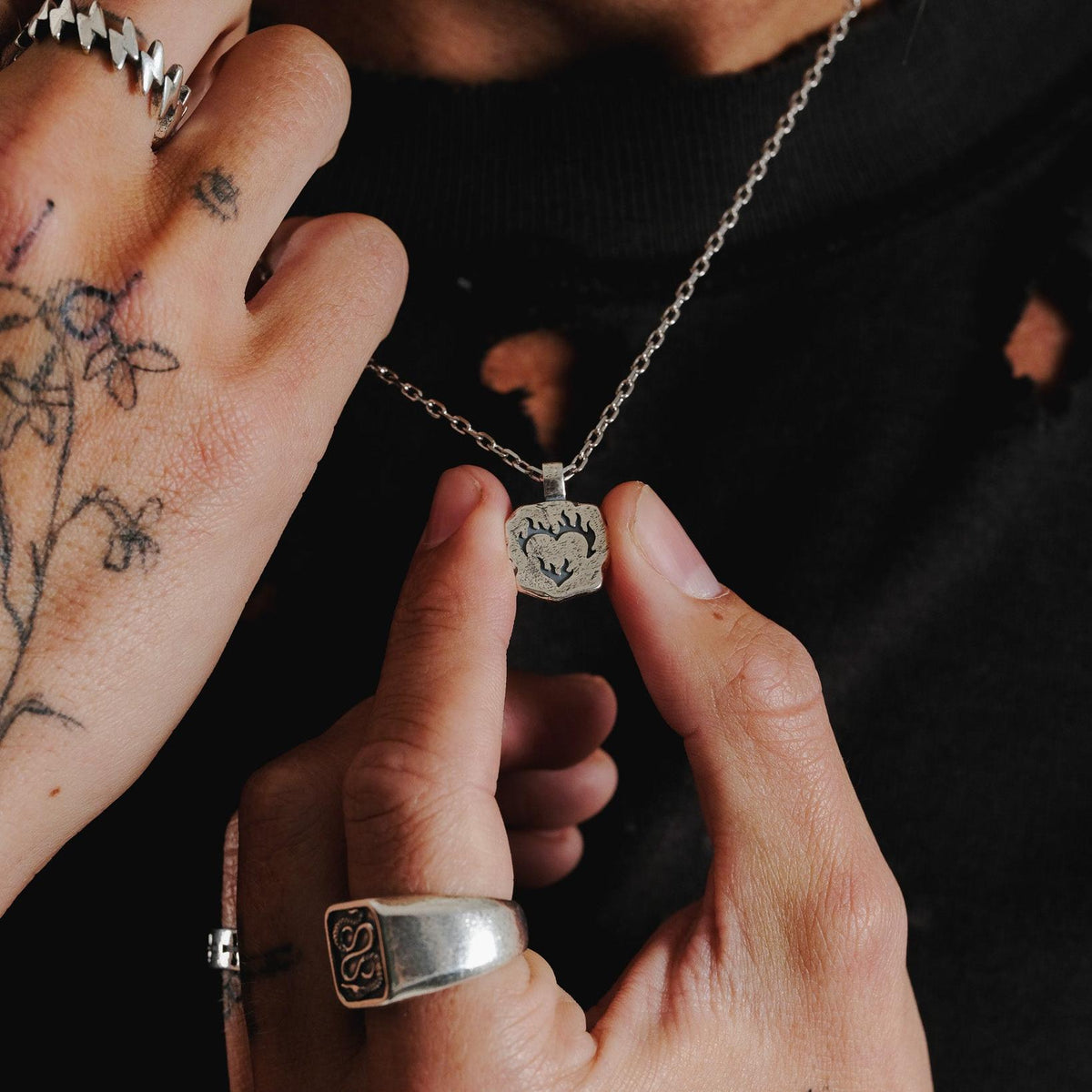 A close-up of a man's hands holding the Billie Jo Ember Pendant, showcasing the detailed craftsmanship of this sterling silver men's jewellery.