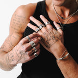 A model with tattoos wears a full Billie Jo jewellery look, including the Slim Link Bracelet, multiple necklaces, and a hand full of silver rings.