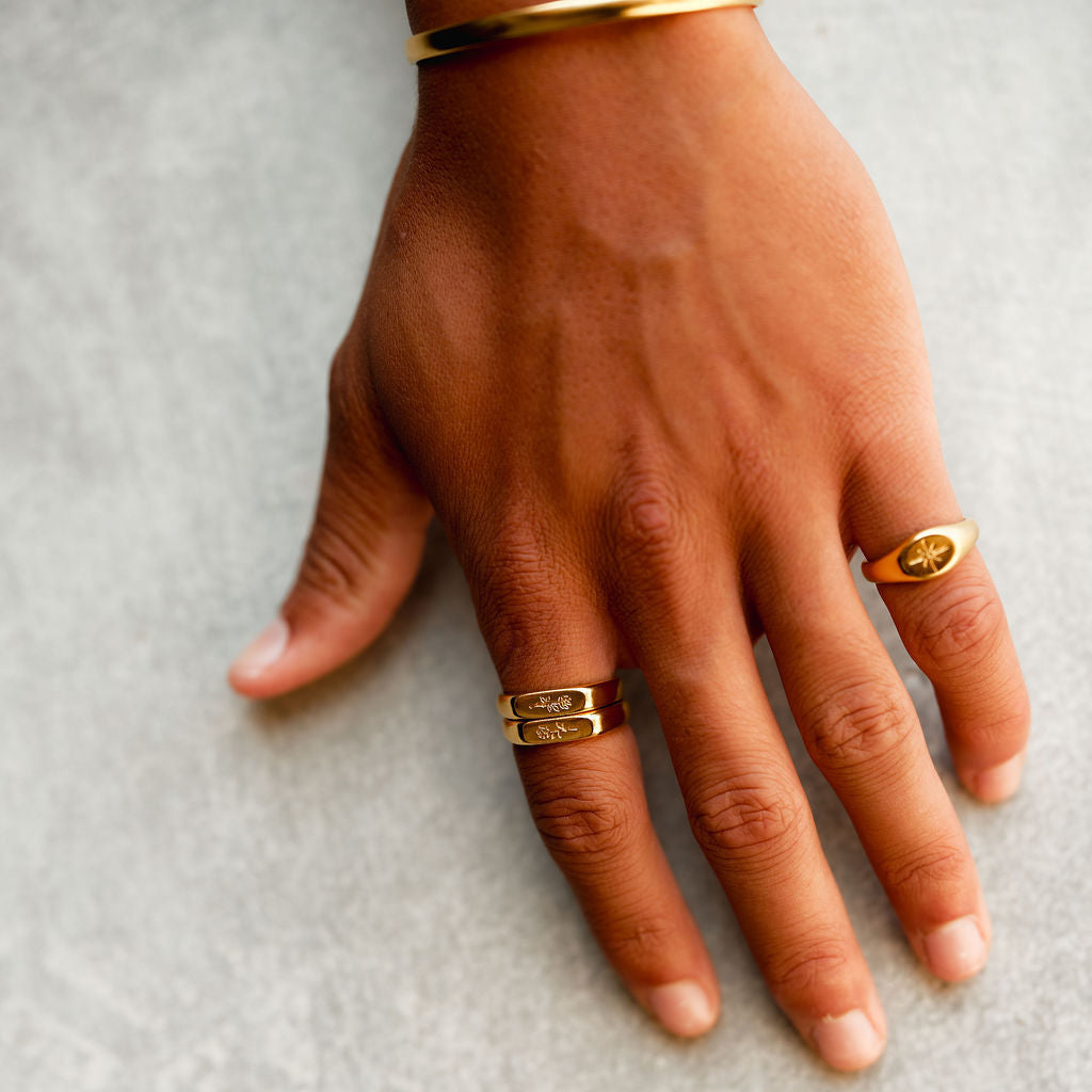 A man's hand adorned with a selection of gold Billie Jo rings, including the Rosa II Ring, showcasing a stacked and curated jewellery style.