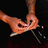 A man's hands clasped, showing off a collection of gold rings, including the detailed engraving of the Billie Jo Union Ring.