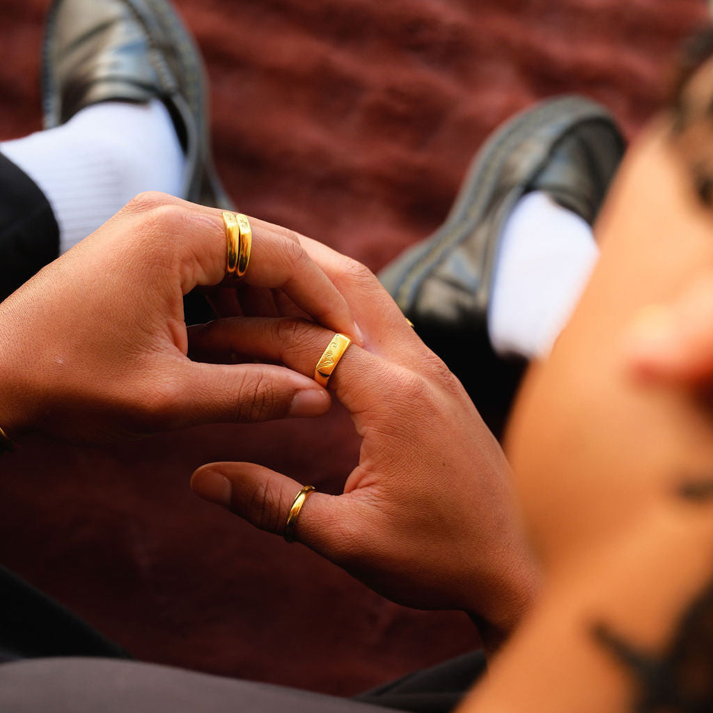 A relaxed lifestyle shot of a man's hands, featuring the gold Union Ring by Billie Jo, paired with other rings for a casual, everyday style.