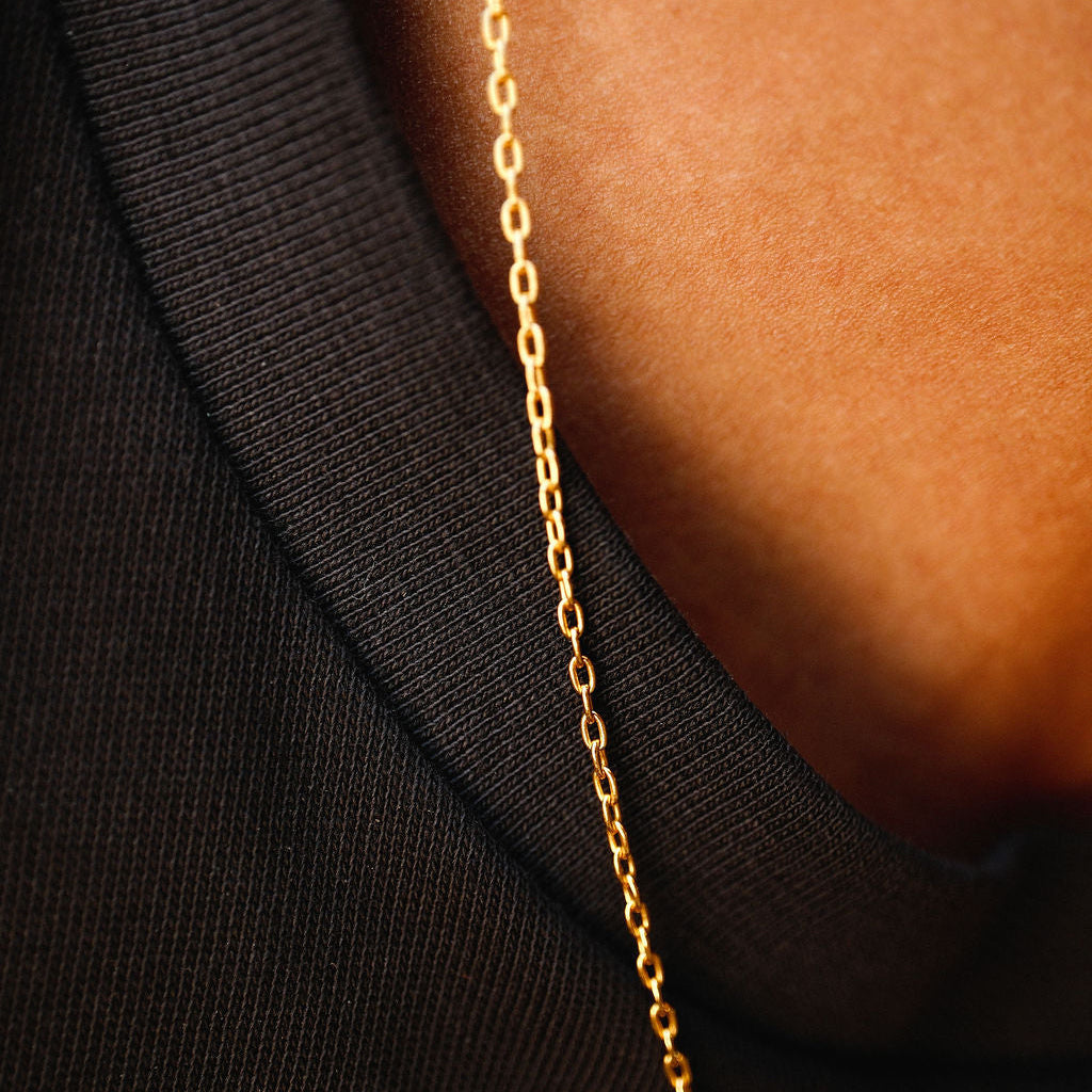 A detailed close-up of the fine 18k gold vermeil chain of the Billie Jo Paradiso Pendant, resting on the collar of a black t-shirt.