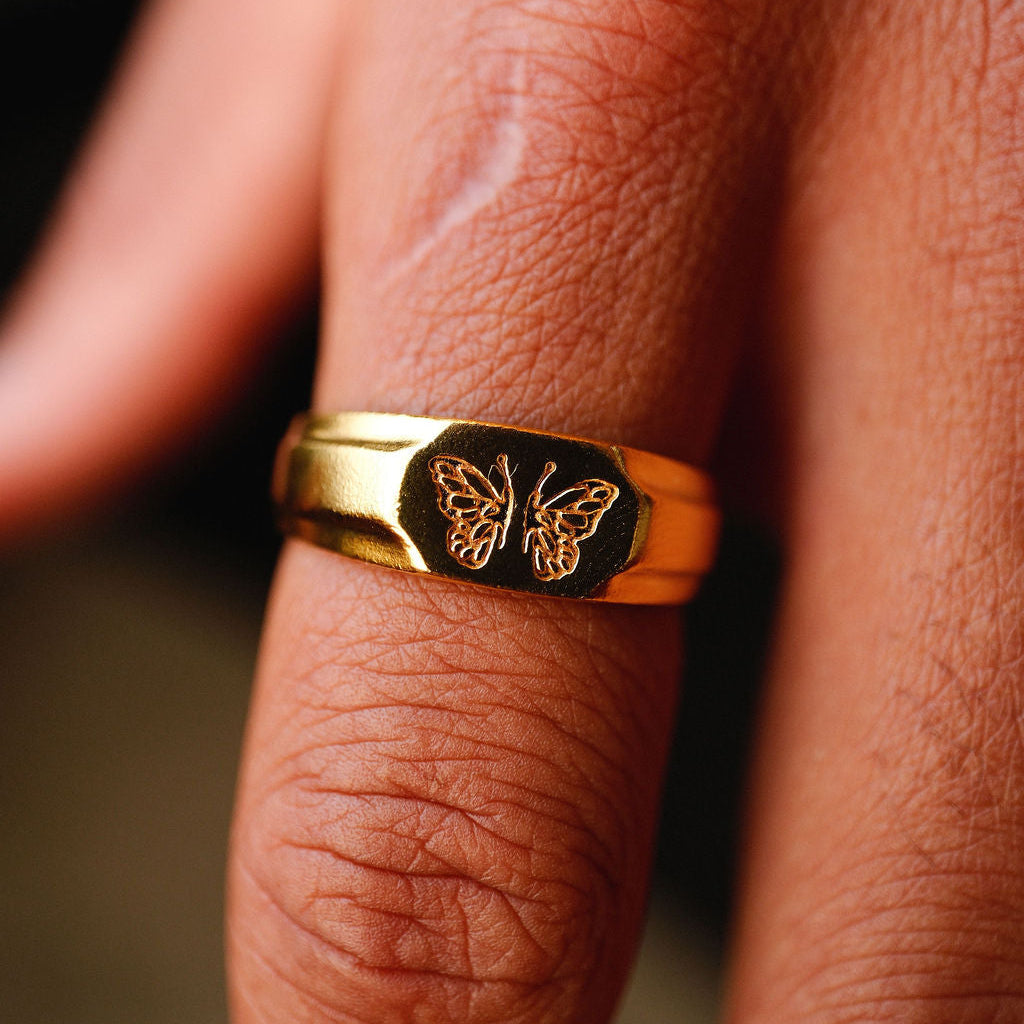 A male model wears the gold Revival Ring from Billie Jo, styled with a white t-shirt. The image showcases the ring's masculine design in a casual, everyday look on the Gold Coast.