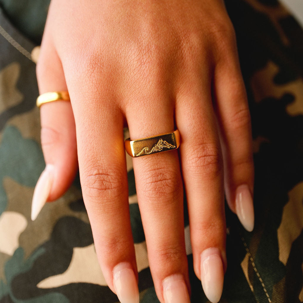A woman's hand with long nails wearing the men's gold Union Ring, demonstrating its versatile and unisex appeal. A unique piece from Billie Jo.