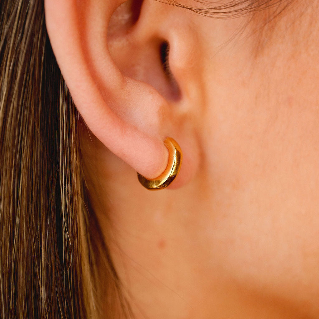 A man wearing the gold Lumina Earring from Billie Jo, shown in a stylish editorial shot that captures the brand's modern and masculine aesthetic.