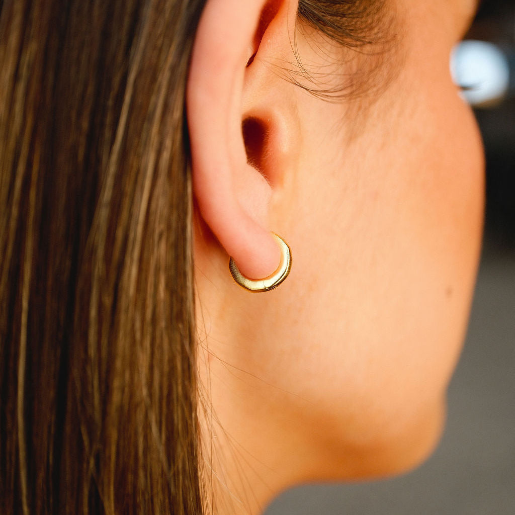 A close-up, on-ear shot of the 18k gold vermeil Lumina Earring, highlighting its polished finish and how it hugs the earlobe for a subtle yet stylish look.