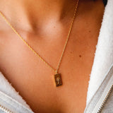 On-person shot of the Billie Jo Paradiso Pendant in gold, worn with a casual grey zip-up hoodie, showing how it sits on the collarbone.