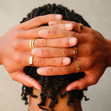 A close-up lifestyle shot of a man's hands, adorned with several gold rings from Billie Jo, including the intricately patterned Gold Relic Ring. Modern men's jewellery.