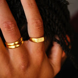 A detailed shot of the gold Momento Ring on a man's hand, resting on his hair, showcasing the ring's design and finish. By Billie Jo.