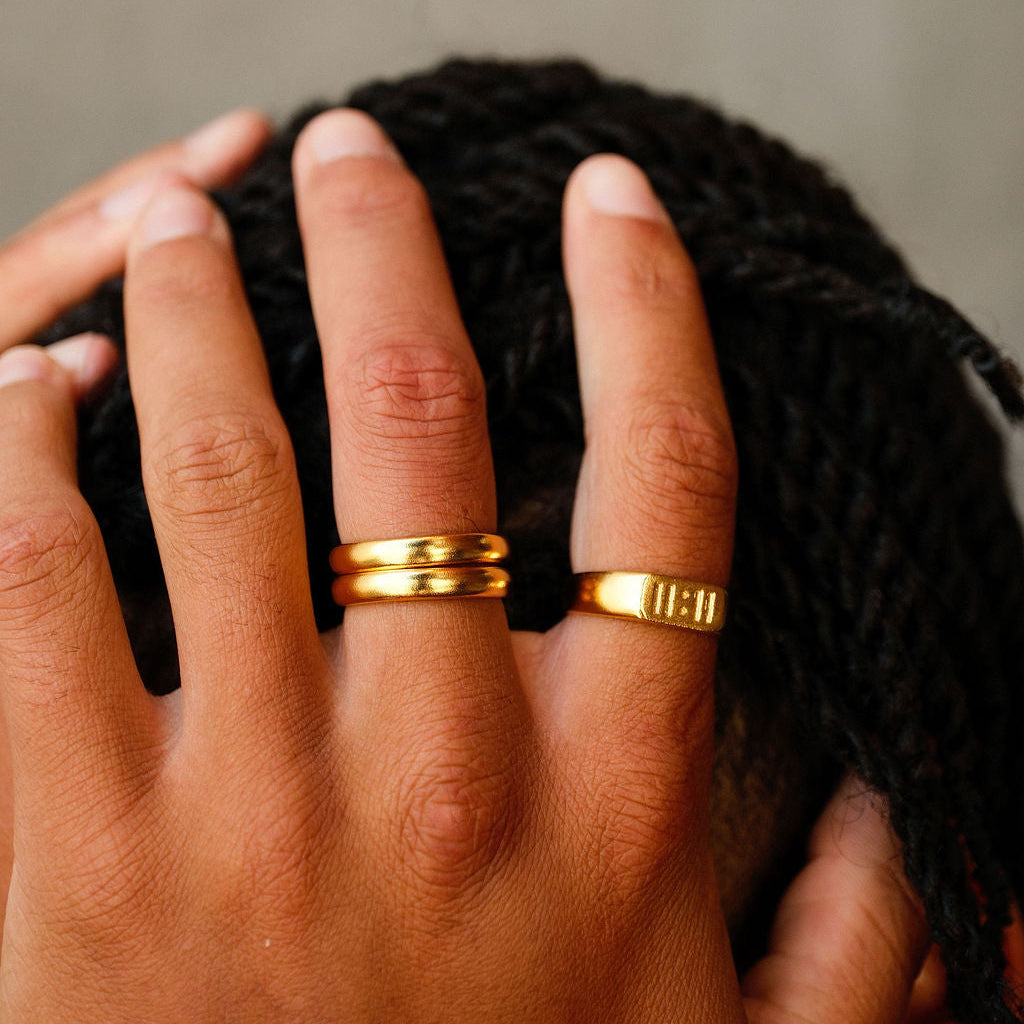 Close-up of a man's hand wearing the Billie Jo 'Stackers - Silver & Gold' rings in 18k gold vermeil, paired with another engraved gold ring.