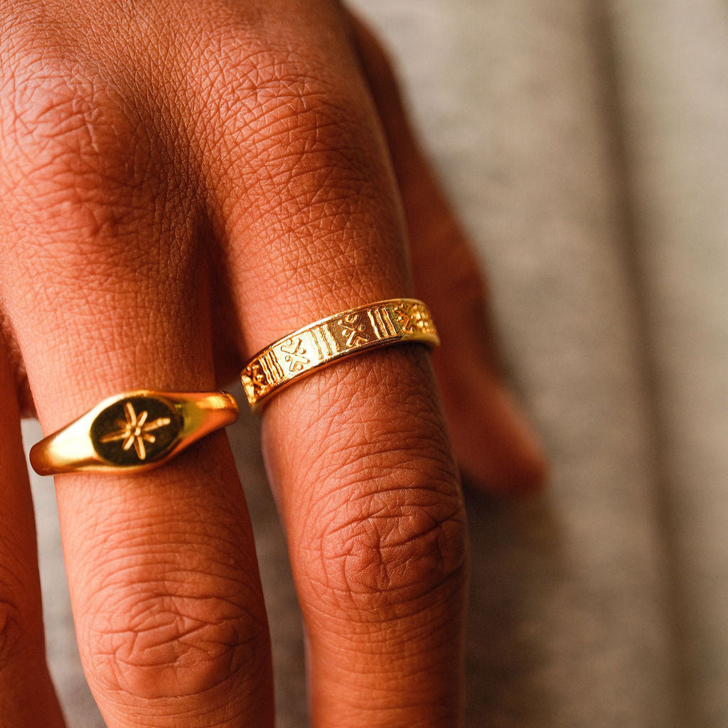 A close-up of the Gold Relic Ring on a man's hand, showing the detailed etched pattern of the 18k gold vermeil. Styled with another gold signet ring from Billie Jo.