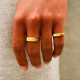 A man's hand wearing the gold Union Ring on his index finger, styled with another gold band. Showcasing men's jewellery from Billie Jo.