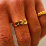 A close-up of the Billie Jo Union Ring in gold, showing the detailed engraving of the mountain and wave design on the signet face.