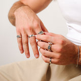 A man's hands adjusting his rings, wearing the Revival Ring and other pieces from Billie Jo, showcasing a styled look for the modern man.