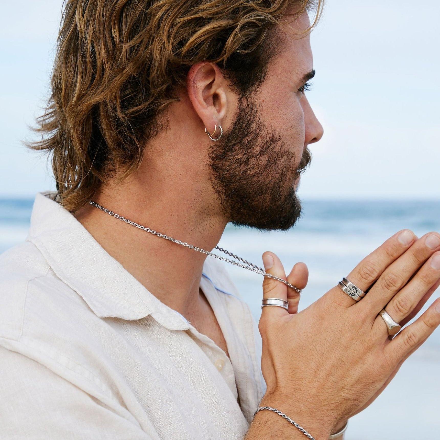 A man on the beach wearing the sterling silver Forge Ring and other jewellery from Billie Jo, creating a stylish, modern, and masculine look.