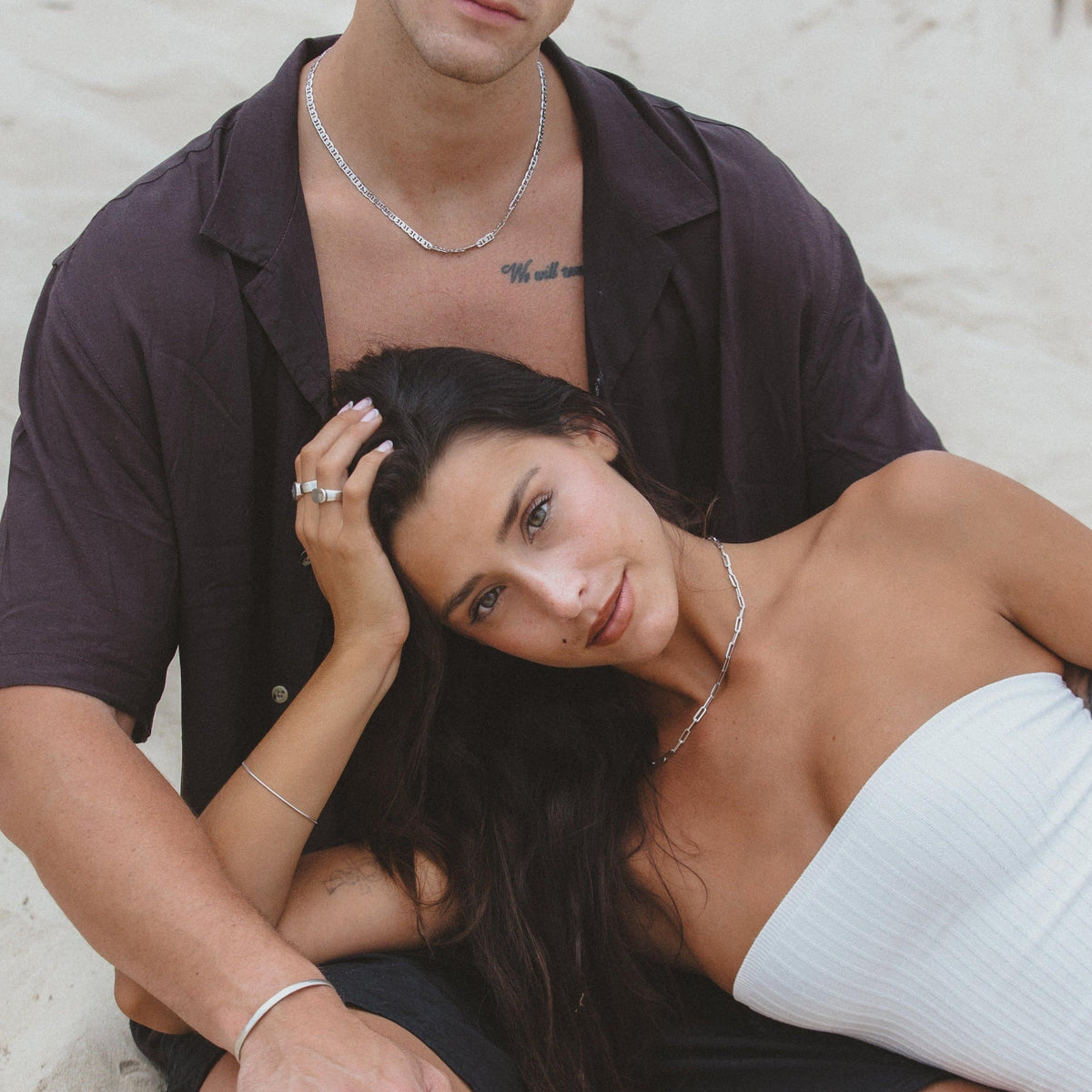 A man wearing the Billie Jo Mariner Necklace embraces a woman on the beach, showcasing a relaxed, coastal lifestyle with Australian jewellery.