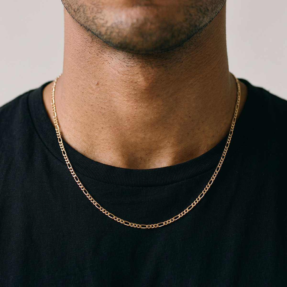 A male model wearing a gold tone stainless steel slim Figaro chain necklace from Australian jewellery brand Billie Jo