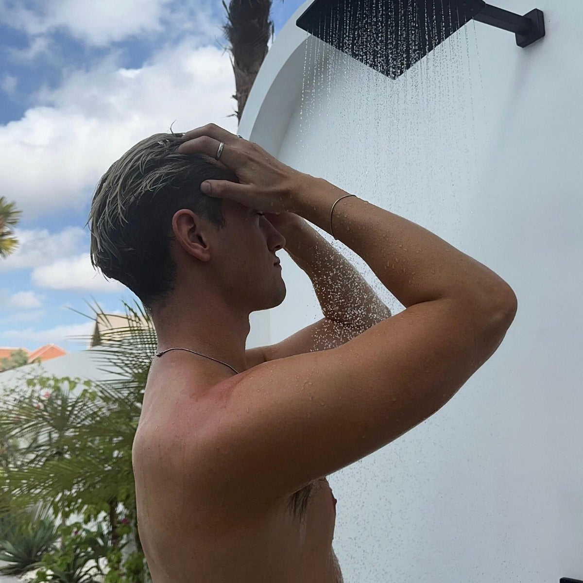 A man wearing the Billie Jo Snake Bracelet in sterling silver rinses his hair in an outdoor shower. This editorial shot captures a relaxed, masculine aesthetic with a focus on the jewellery's everyday wearability.