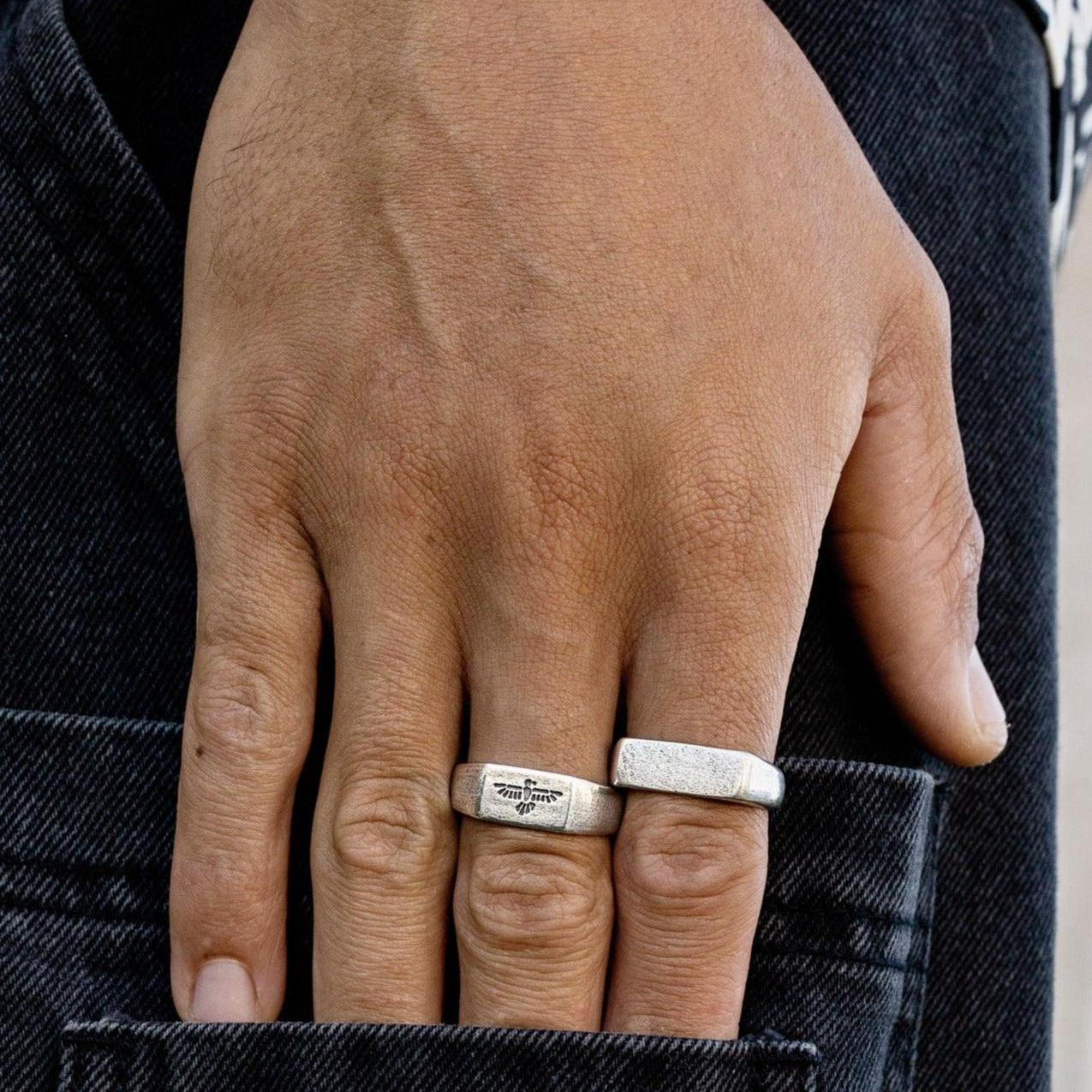 A man's hand, wearing the sterling silver Essence Ring from Billie Jo, resting casually in the back pocket of his dark-wash denim jeans.