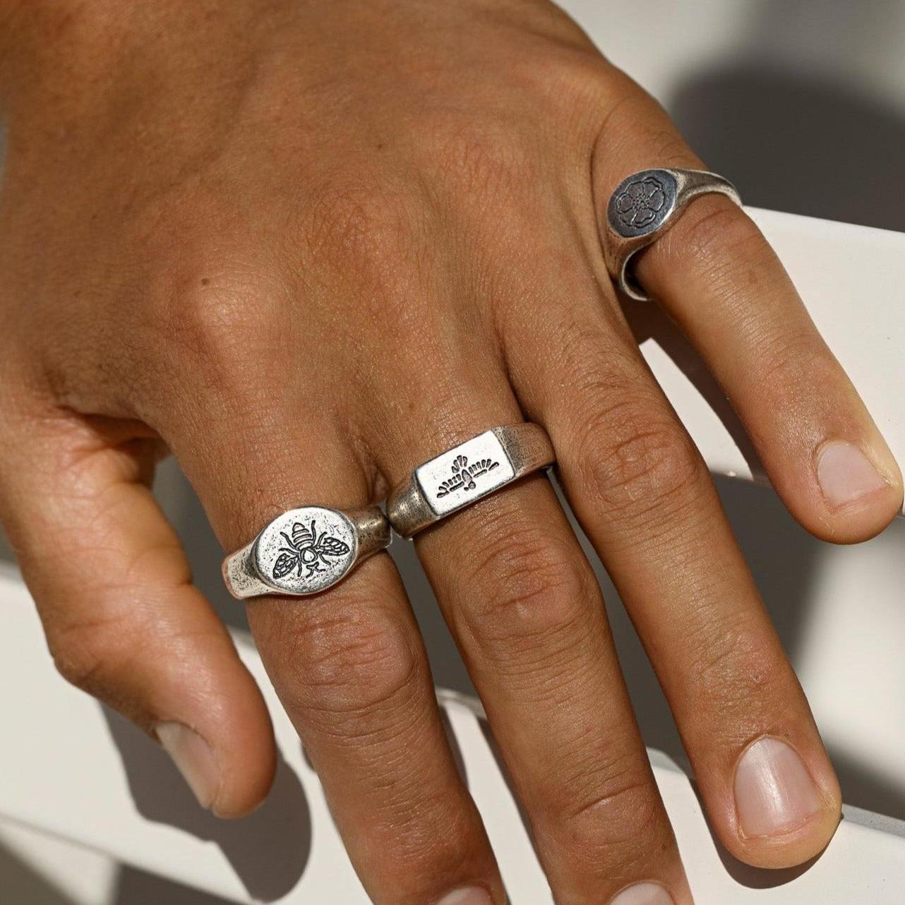 An on-hand shot of the sterling silver BEE THERE RING, styled with other signet rings from Billie Jo, against a clean white background.