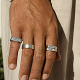 A man's hand wearing the sterling silver Union Ring stacked with other minimalist rings from Australian jewellery brand Billie Jo. Close-up on hand.