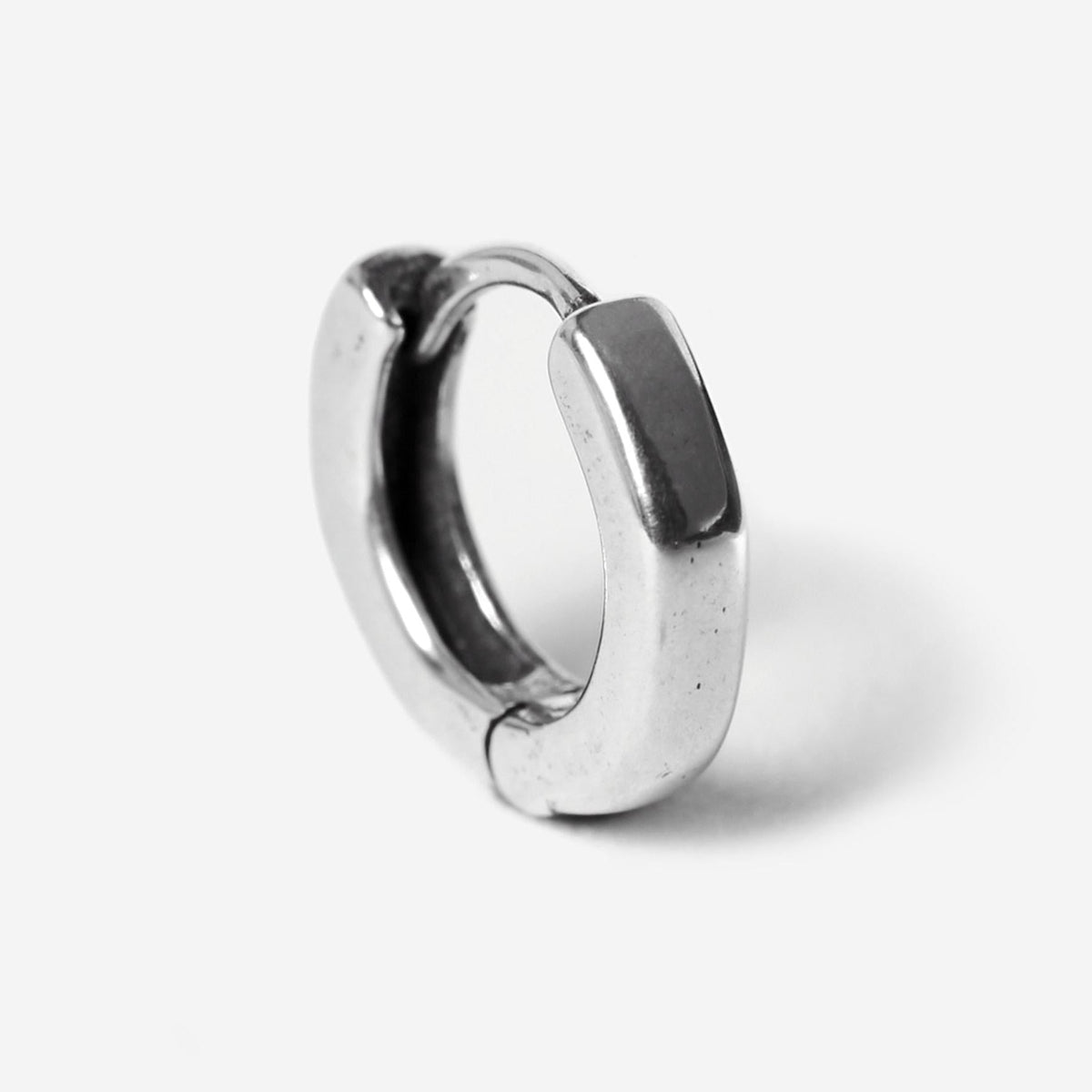 A single sterling silver Billie Jo Lumina hoop earring, showcasing its smooth, polished finish and minimalist design against a stark white background.