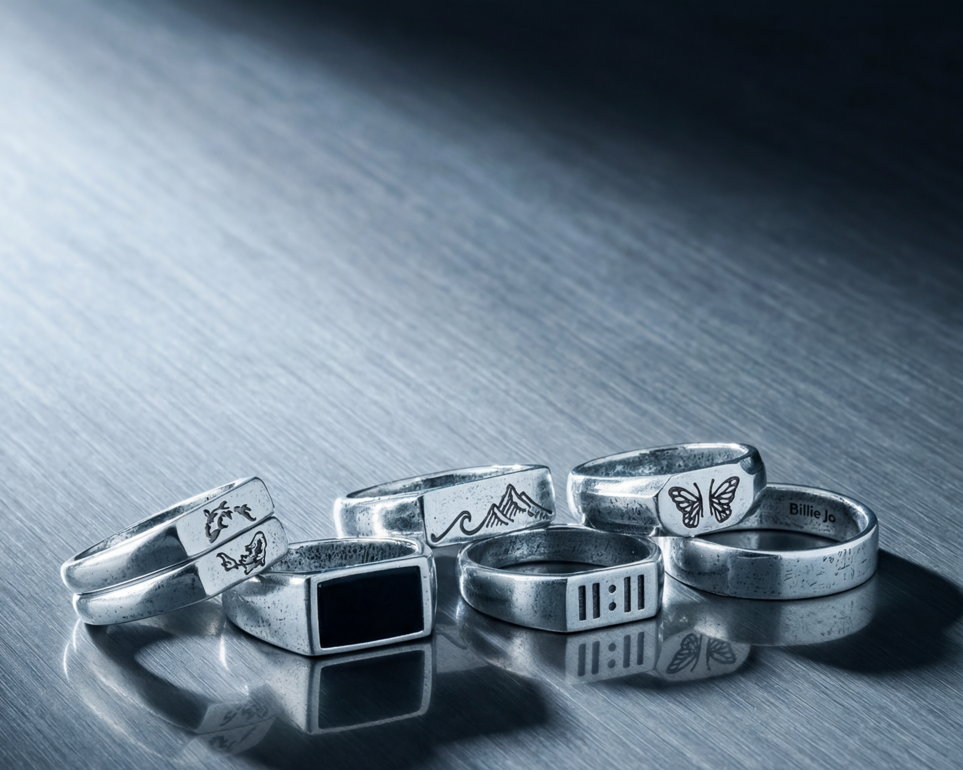 Collection of silver rings on a reflective surface with a dark background