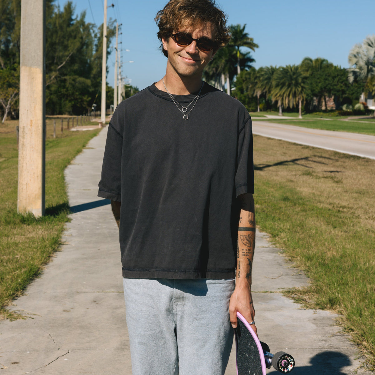 A man wearing two Billie Jo Ouroboros Pendants with a skateboard, showcasing the brand's modern, coastal aesthetic. Australian men's jewellery.