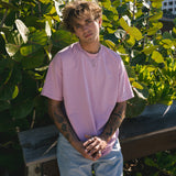 Campaign image for Billie Jo showing a model in a pink tee and the Ouroboros Pendant, standing against lush green foliage on the Gold Coast, Australia.